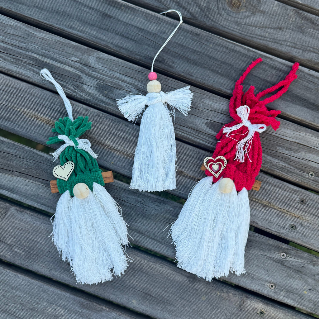 Three decorative gnomes made of yarn on a wooden surface